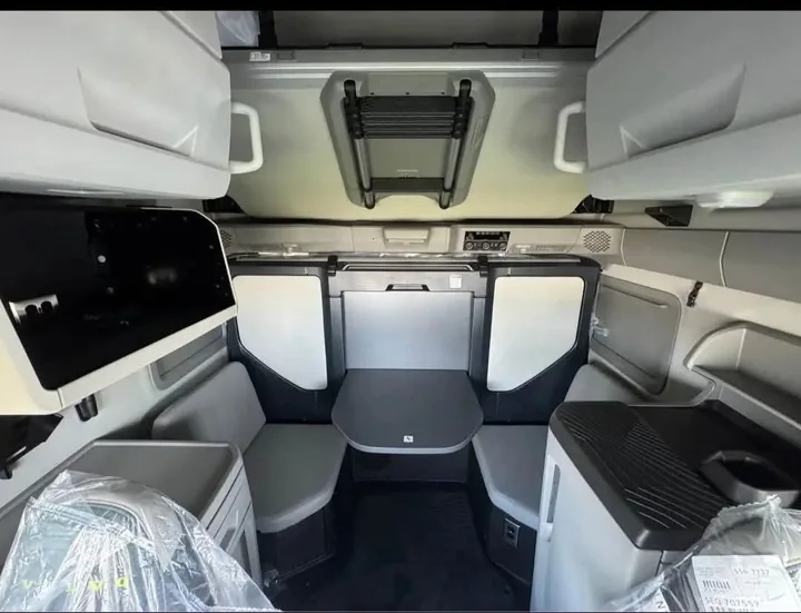 Truck cabin with seating, a table and overhead storage
